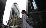 A solitary pedestrian walks past the Gherkin office block in the City
