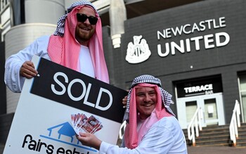 Newcastle United supporters dressed in robes pose with 'sold' placards as they celebrate the sale of the club to a Saudi-led consortium