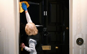 A cleaner polishes the door of Number 11, Downing Street, UK