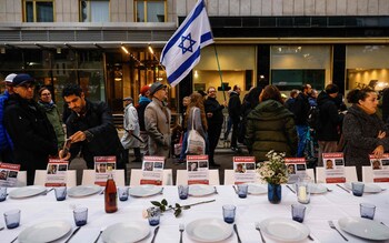 A participant waves the flag of Israel at a display of a Shabbat table in solidarity with  hostages abducted by Palestinian group Hamas