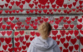 A girl looks at messages and hearts on the National Covid Memorial Wall, dedicated to those who lost their lives to Covid-19